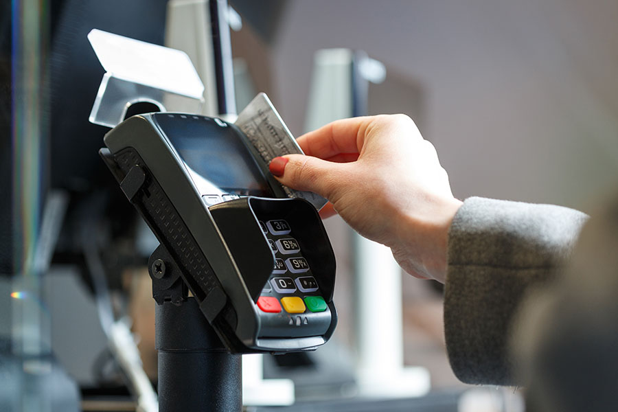 Female hand swiping a card in a card terminal doing payment. Retail payment. Consumer and financial concept