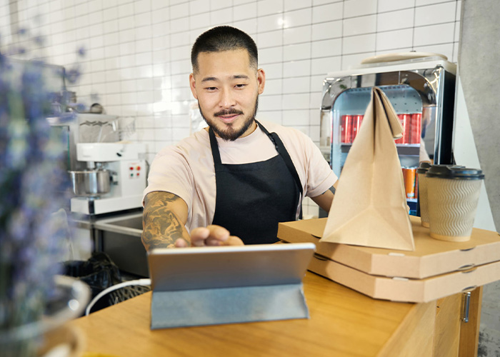 Friendly cafe shop worker smiling while making a receipt for a food takeaway order