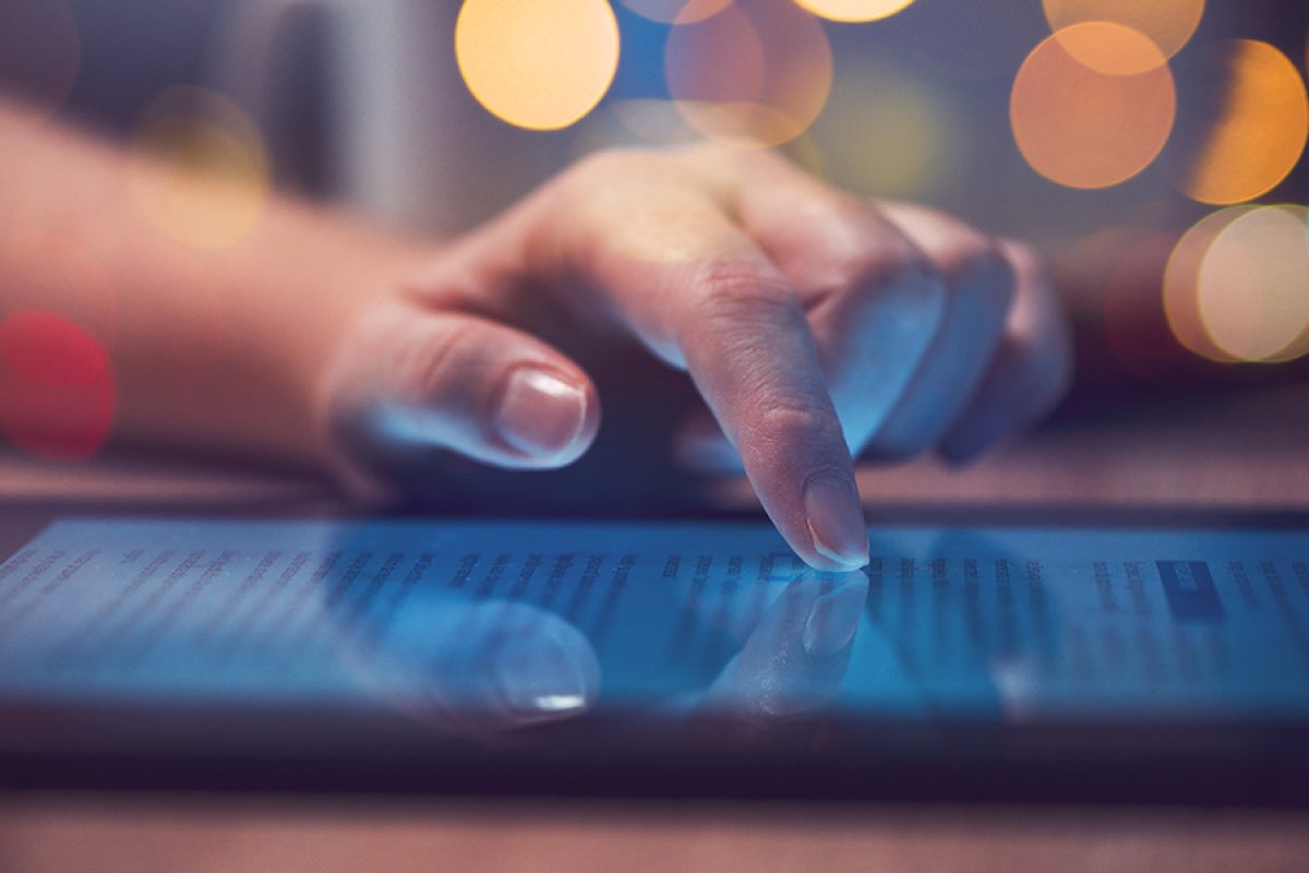 Woman reading online news on digital tablet, close up of hands using device