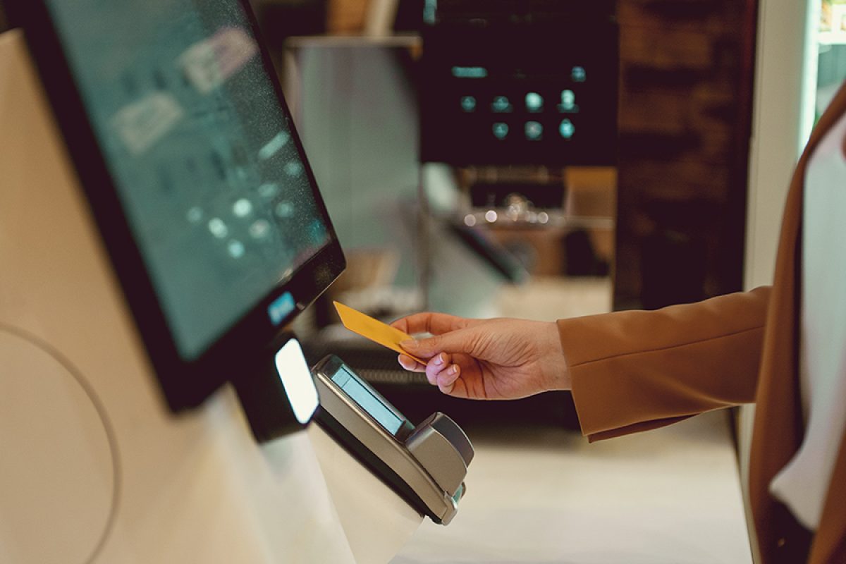 Woman pays at self-checkouts in supermarket.